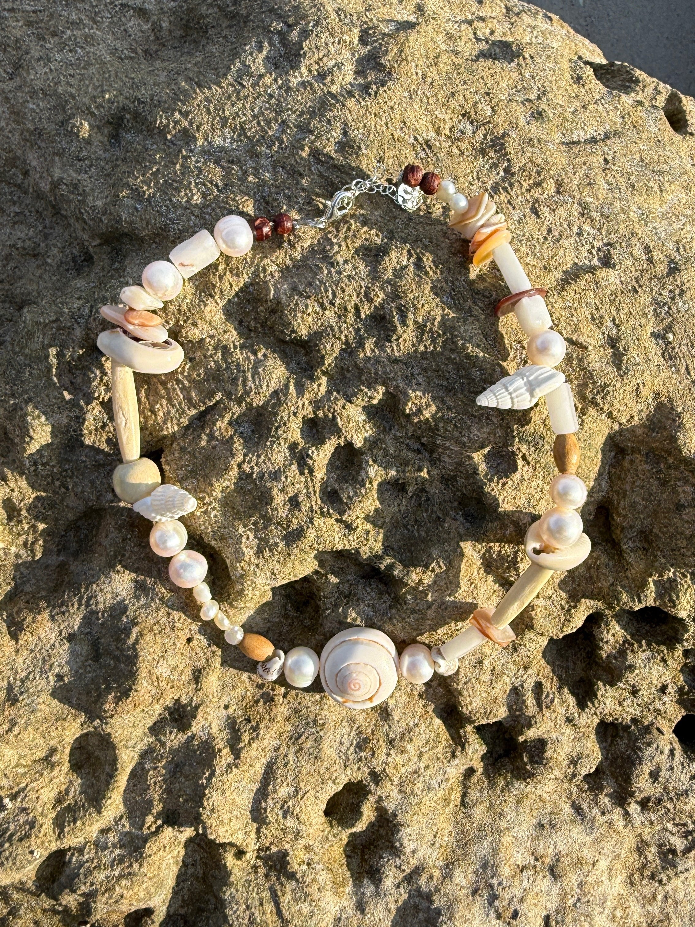 Close-up of seashell and pearl beads on choker necklace – lightweight vacation accessory.

Seashell pearl choker layered with matching bracelet – boho coastal jewelry for ocean lovers.