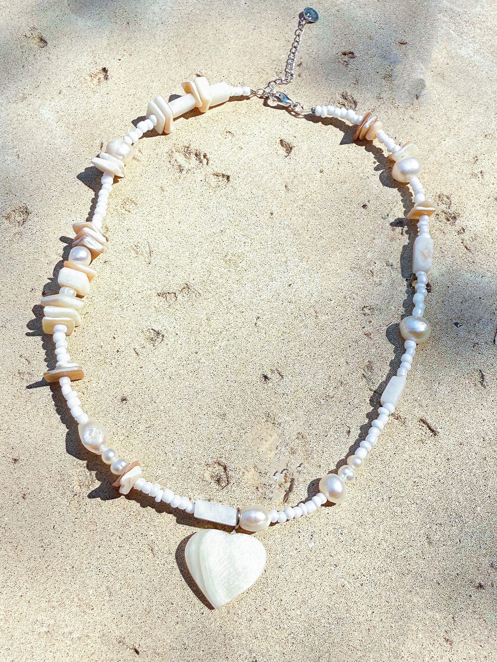 Handmade shell choker necklace with a heart-shaped mother of pearl pendant, crafted for boho beachwear and summer gifting.