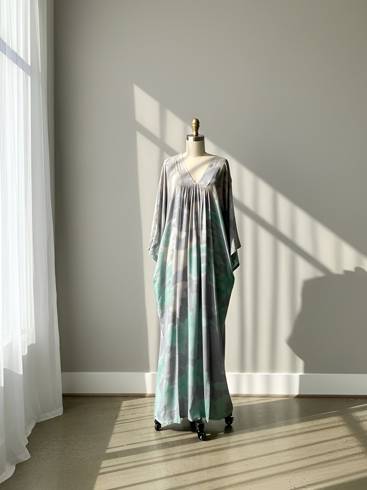 Long time dye dress on a mannequin against a neutral wall with sunlight casting shadows.