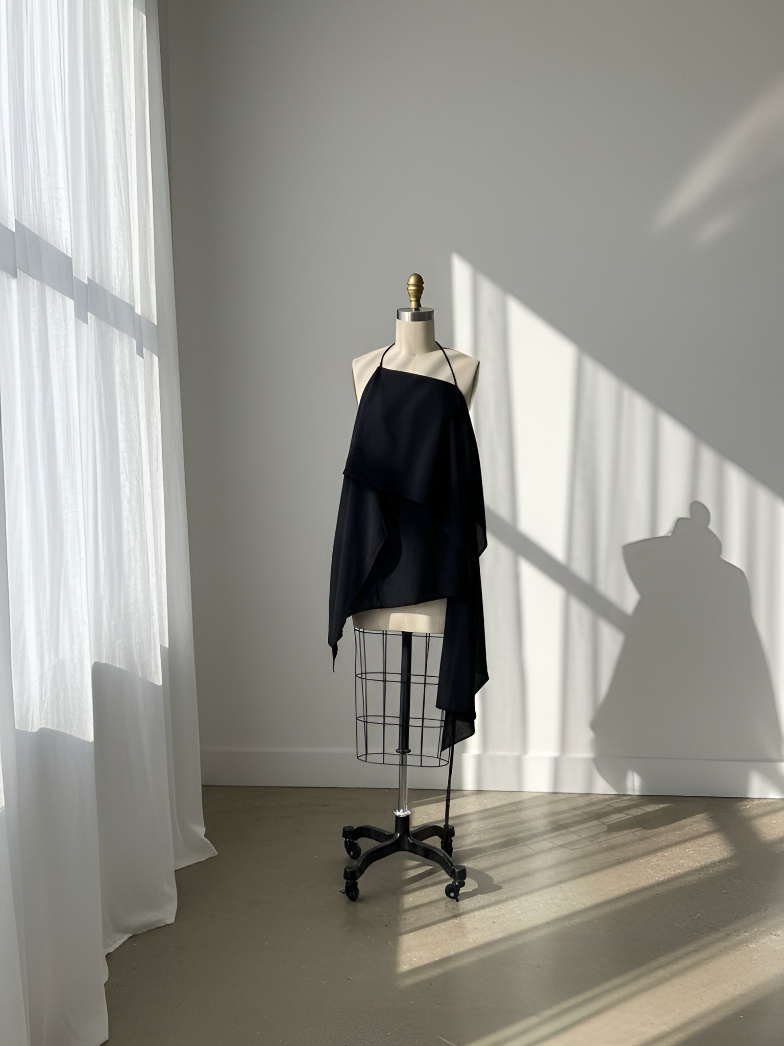 Woman in a black flowy kaftan top standing on a balcony with a scenic view of trees and water.