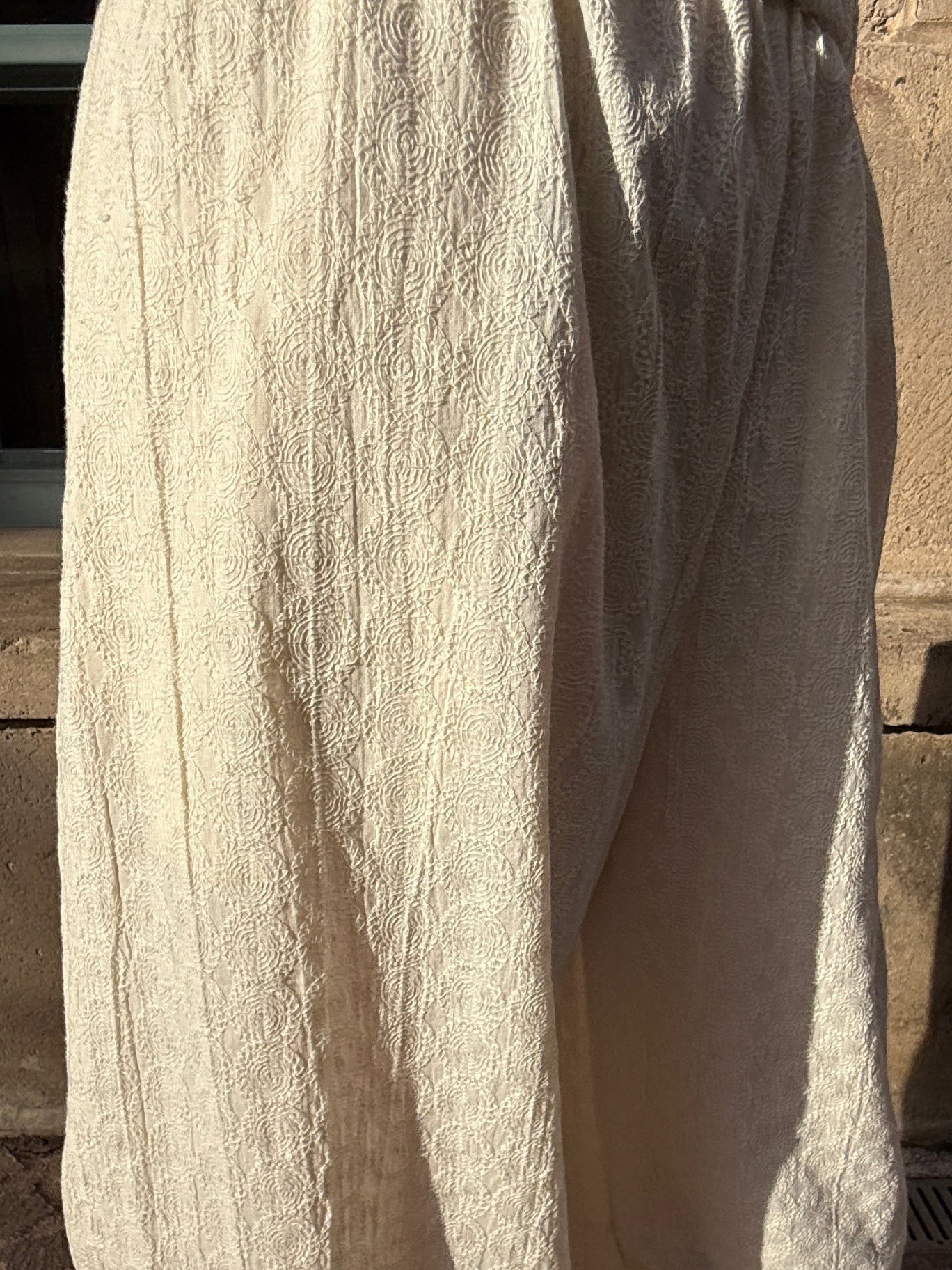 Close-up of beige textured lace pants with a blurred background