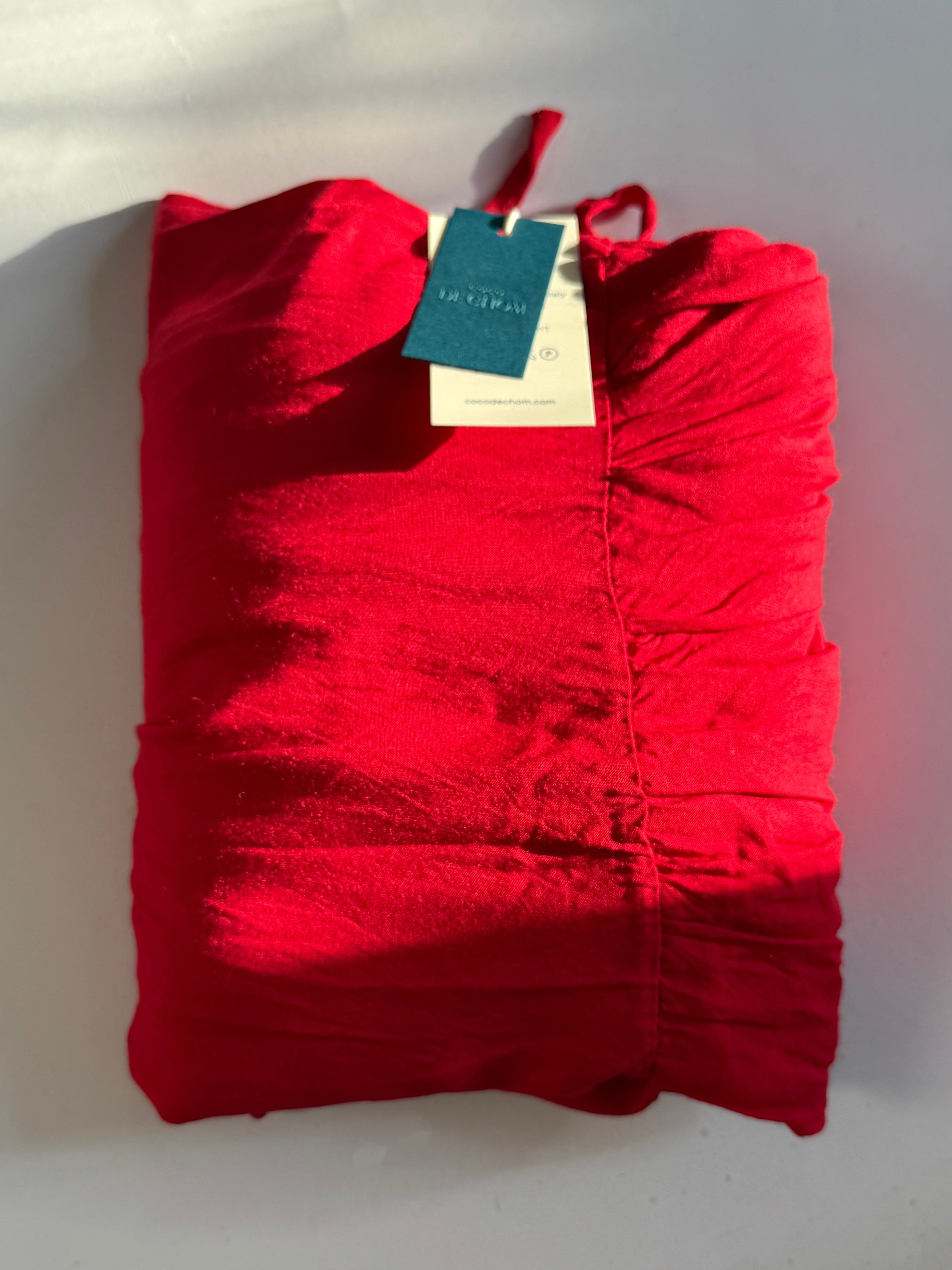 Red hand-dyed backless maxi dress with tie shoulders, ruffle hem, and flowy oversized fit for resort wear with a tag on a white background