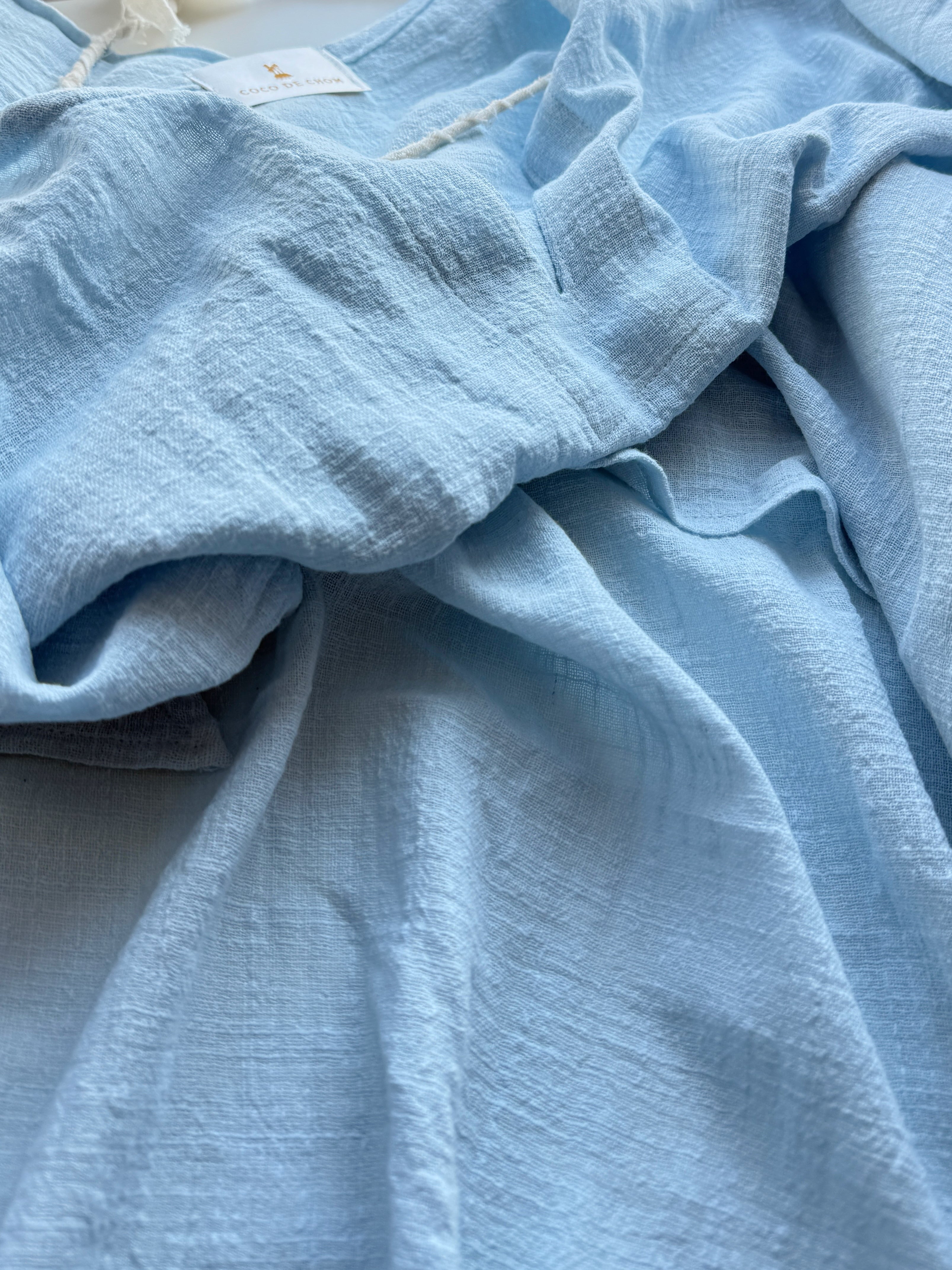 Close-up of AMARA cotton linen kaftan top light blue worn as beach coverup relaxed fit COCO DE CHOM