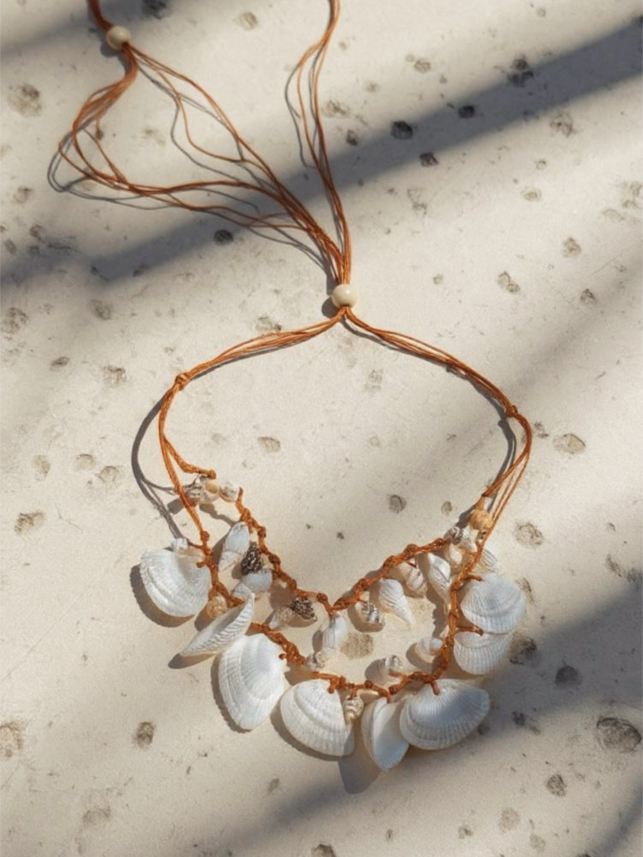 This is handmade white seashell choker necklace with boho beach style, photographed outdoors in natural light, styled with relaxed resortwear.