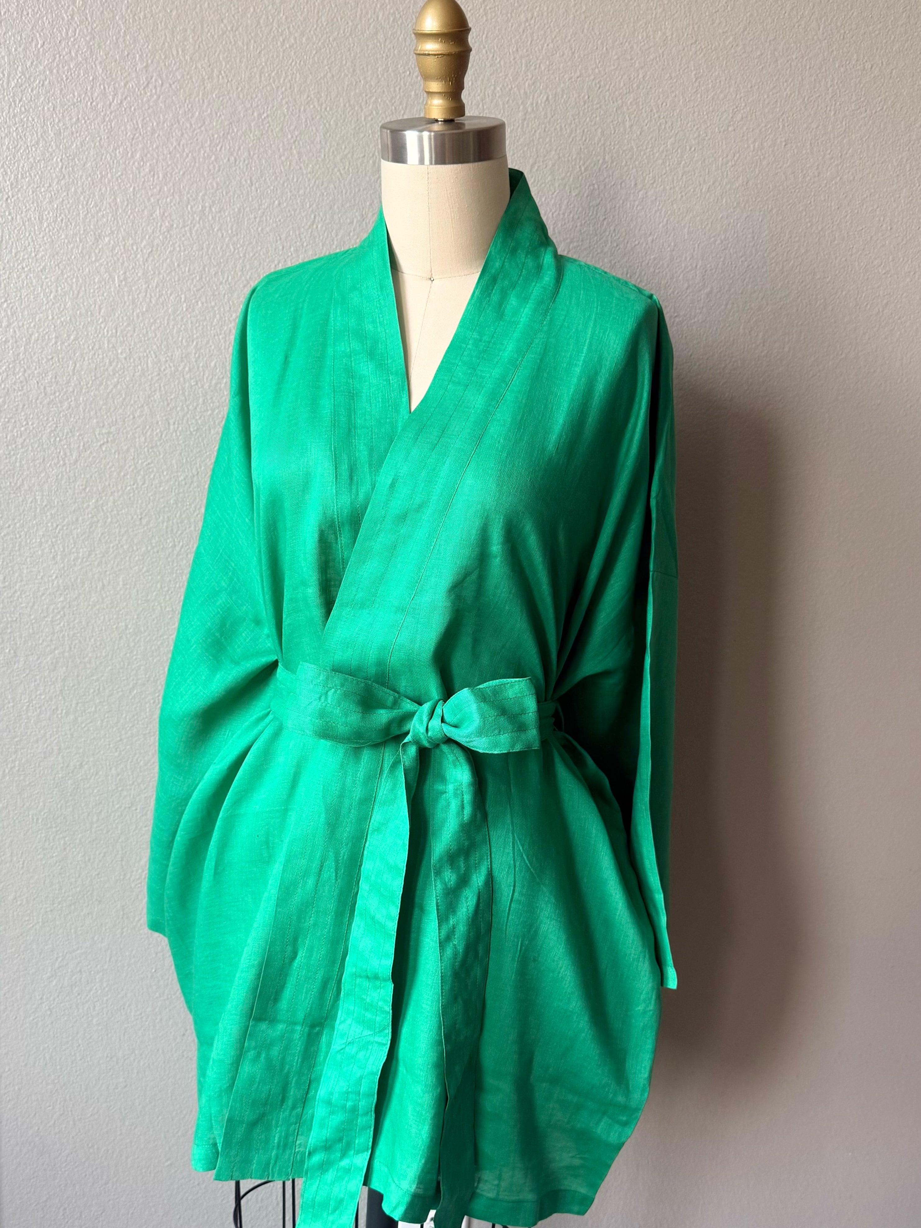 Emerald green linen kimono jacket with oversized wrap fit, wide sleeves, pockets, and waist tie, styled as a resort robe and beach cover up
