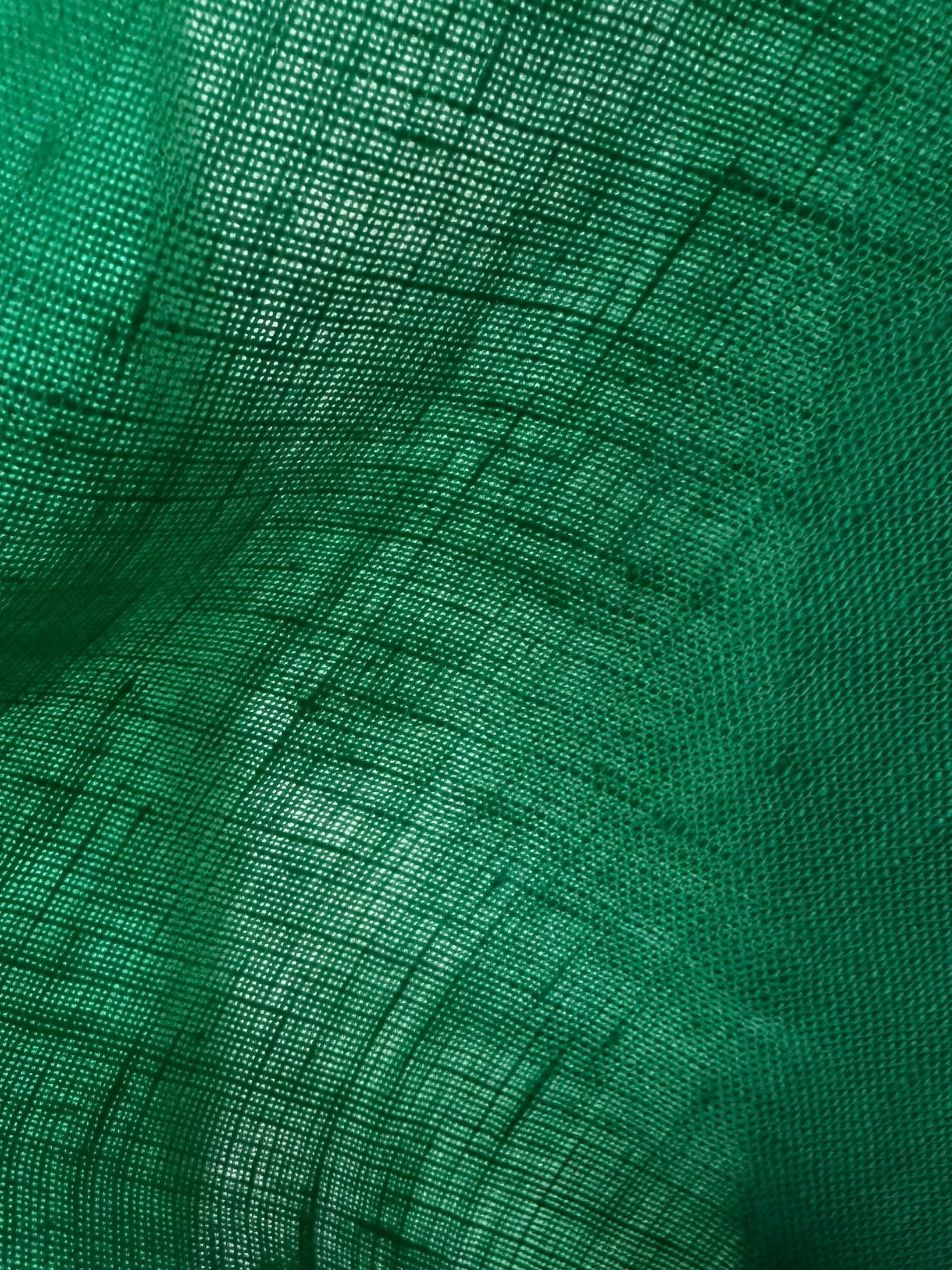 A close-up of green mesh fabric with a fine grid texture and soft folds.
