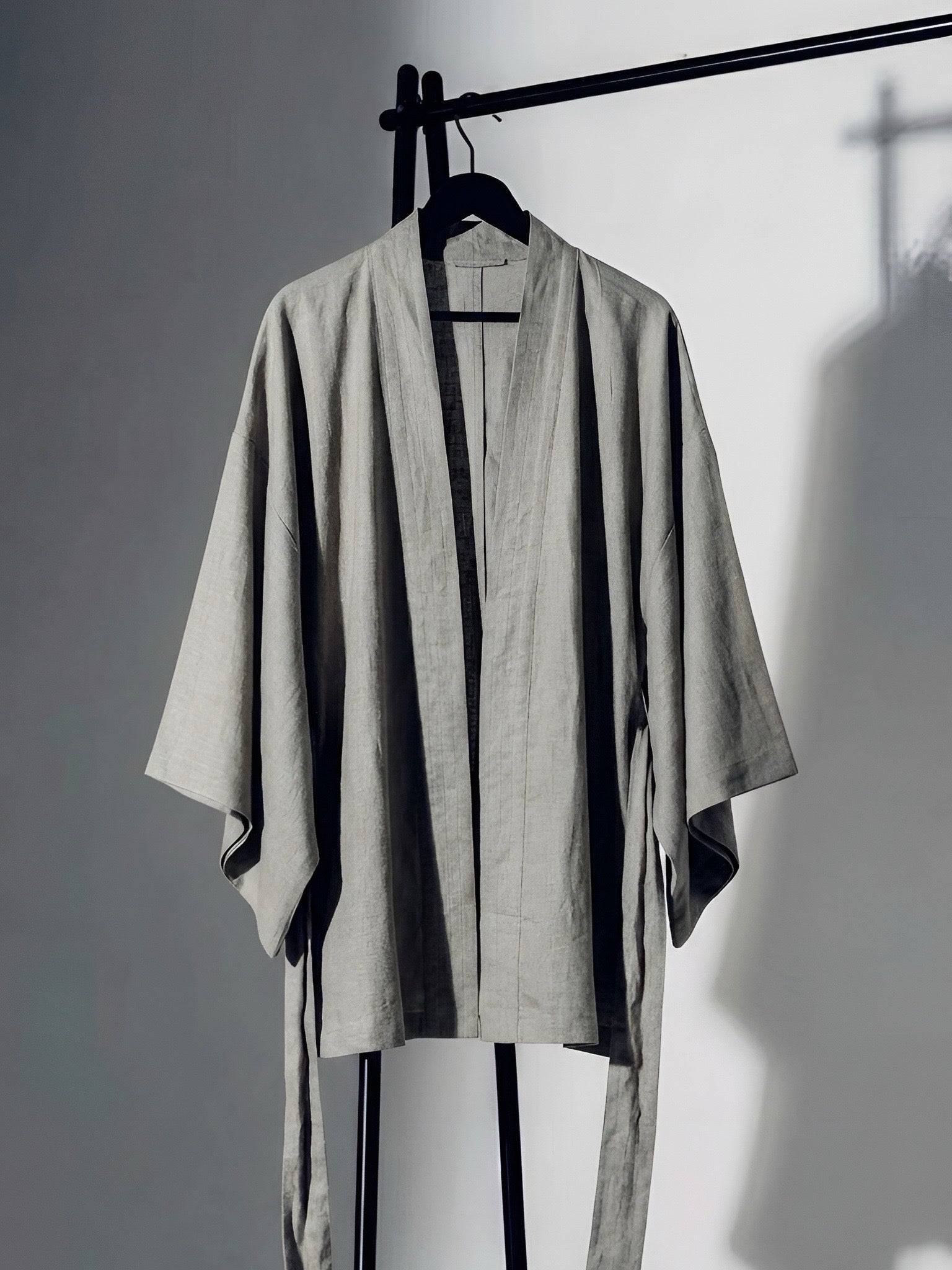 Natural gray linen kimono jacket with oversized wrap fit, wide sleeves, pockets, and removable waist tie, styled as a resort robe and everyday linen layer.