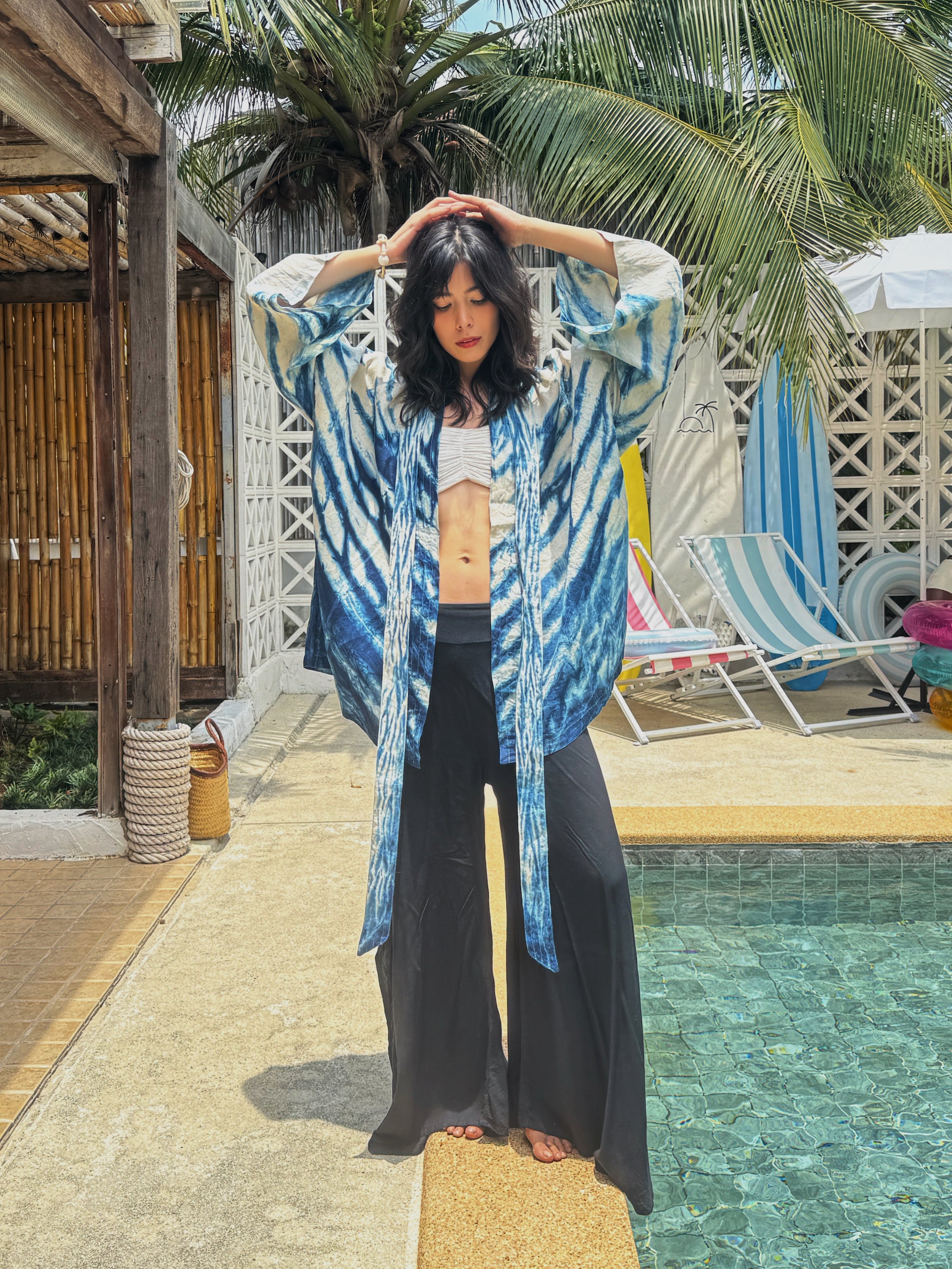 Model wearing the Limited Edition Kira Indigo Linen Kimono, artisan handmade with natural indigo Shibori tie dye. Features wide sleeves, a linen belt, and a relaxed Japanese kimono wrap silhouette. Perfect for sustainable fashion lovers seeking a boho kimono jacket or limited edition slow fashion robe from COCO DE CHOM.