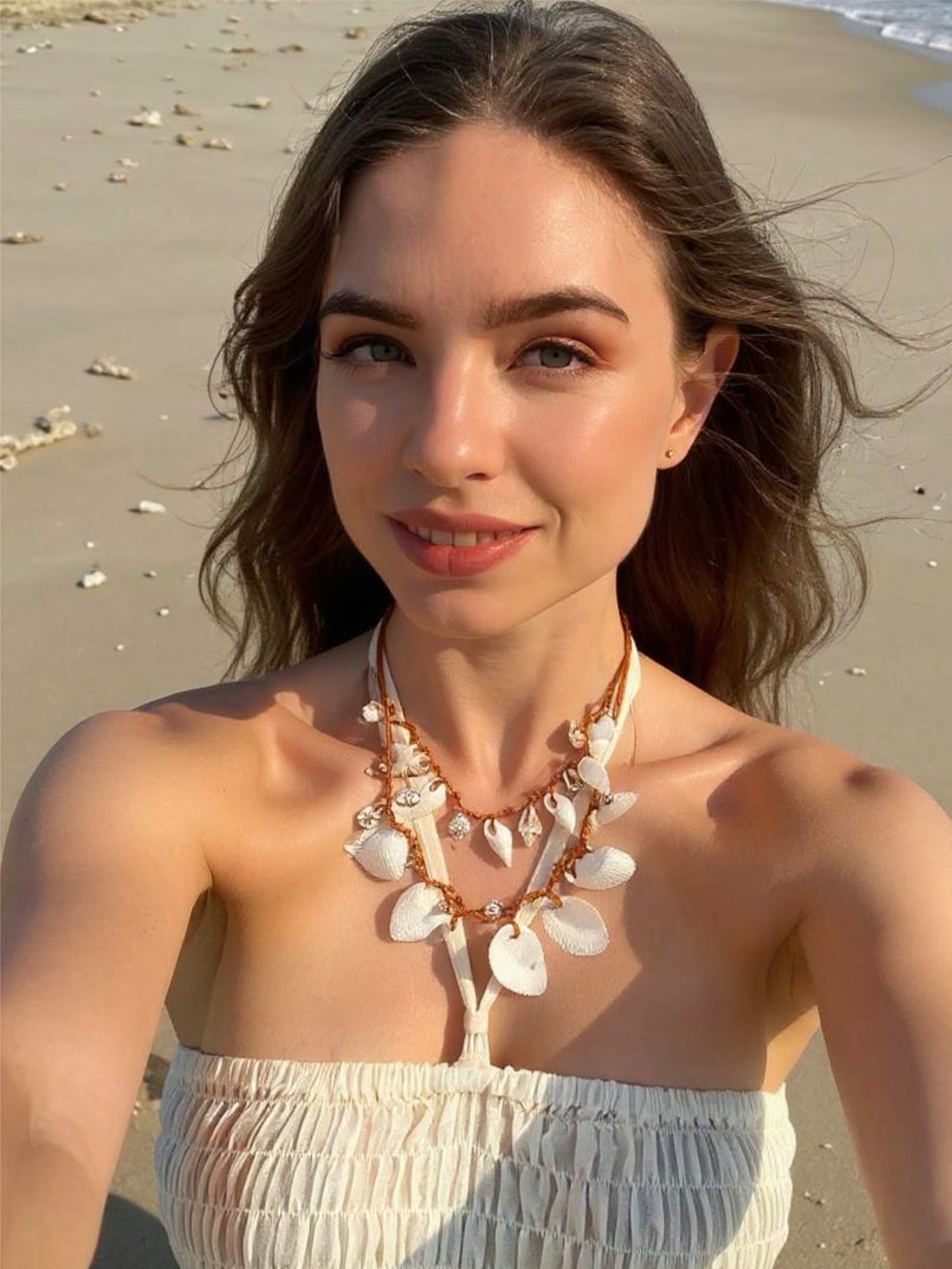 Model wearing a handmade white seashell choker necklace with boho beach style, photographed outdoors in natural light, styled with relaxed resortwear.