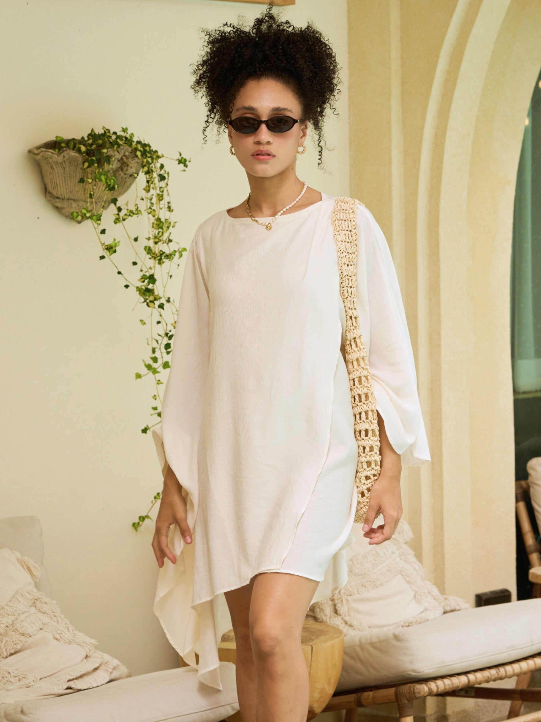 Person wearing a white mini kaftan top beach cover up tunic, one size fits most, long sleeves with high-low hem, lightweight resort vacation wear in a resort