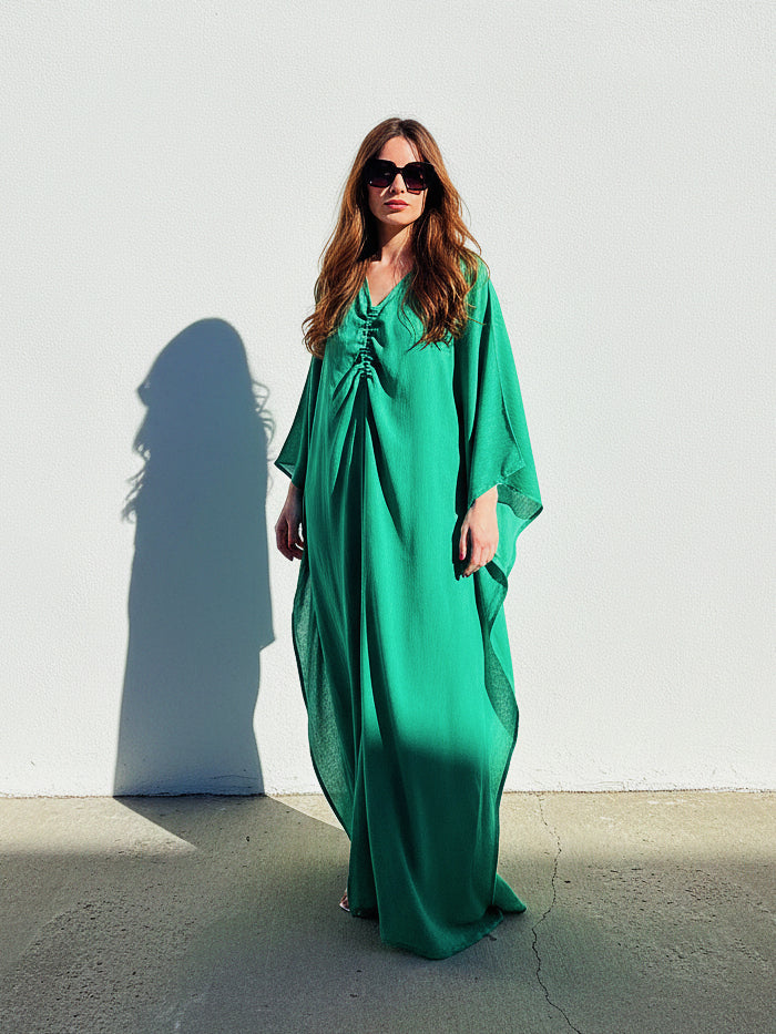 Woman wearing an Emerald green kaftan maxi dress by COCO DE CHOM, oversized plus size resort wear with long sleeves, flowy drape, and beach cover up maxi silhouette