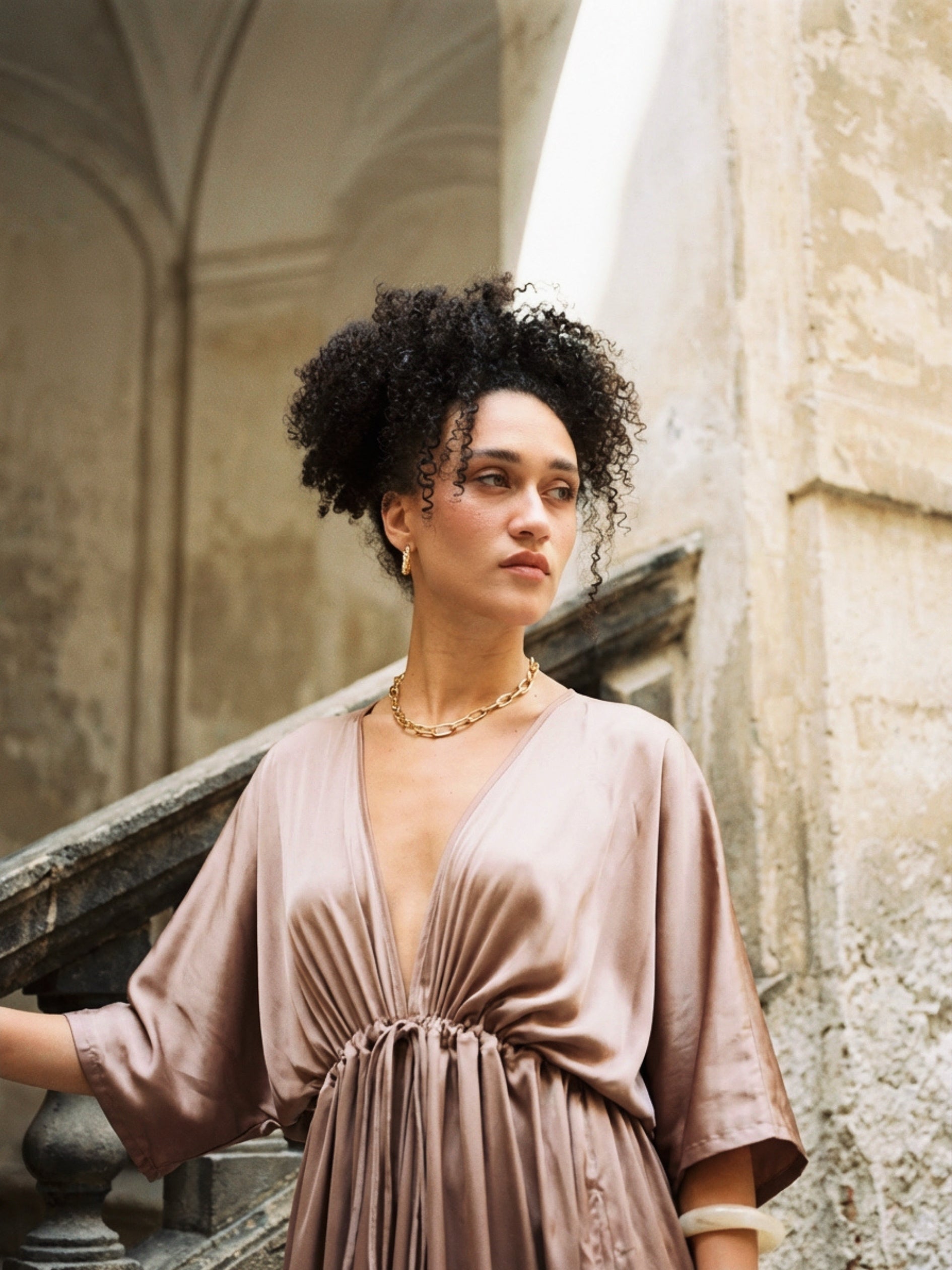 Woman wearing a mocha rose kaftan maxi dress with deep V-neck and self-tie waist, styled as resort wear and a beach wedding guest dress