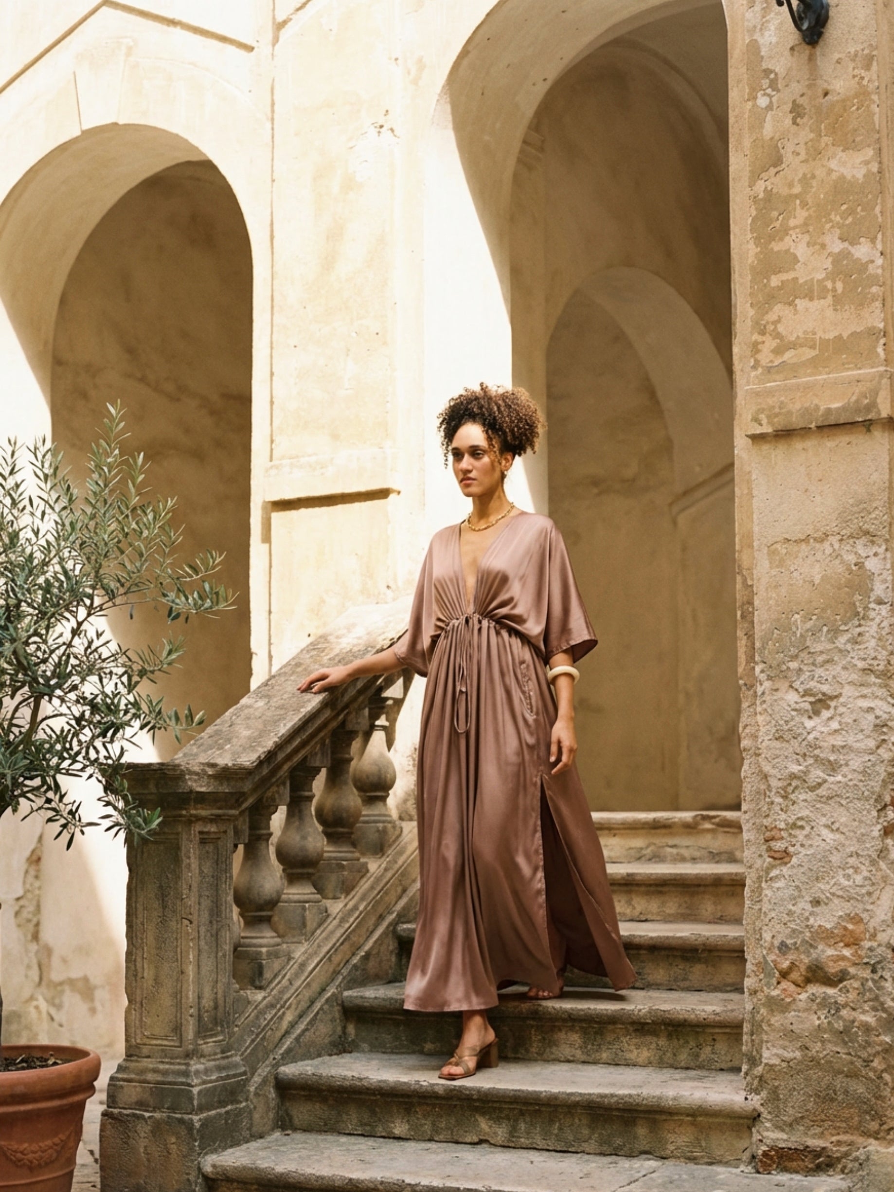 Woman wearing a mocha rose kaftan maxi dress with deep V-neck and self-tie waist, styled as resort wear and a beach wedding guest dress