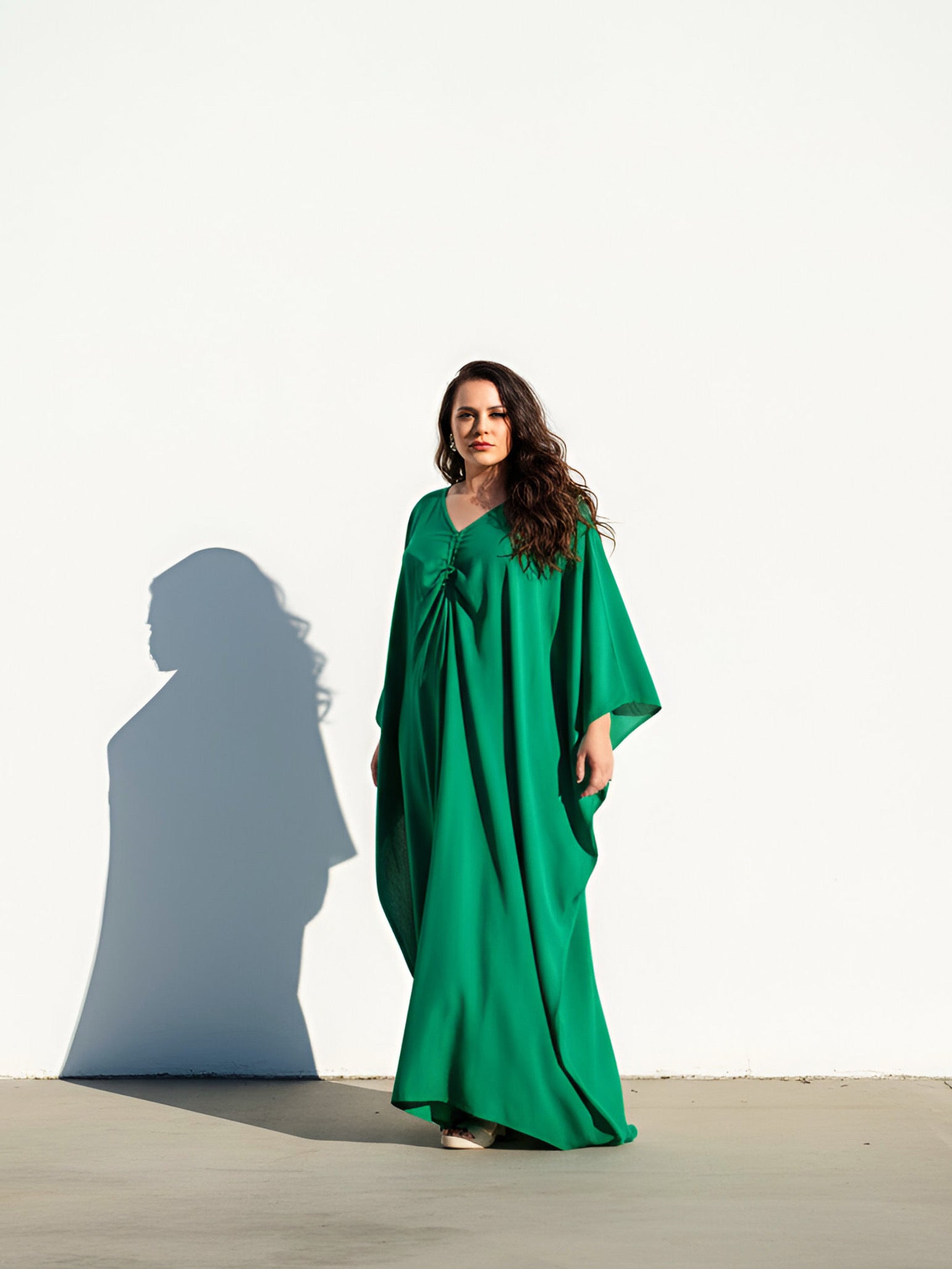 Woman in an Oversized emerald green long sleeve caftan maxi dress, plus size boho resort dress and cruise vacation outfit with airy flowy maxi movement