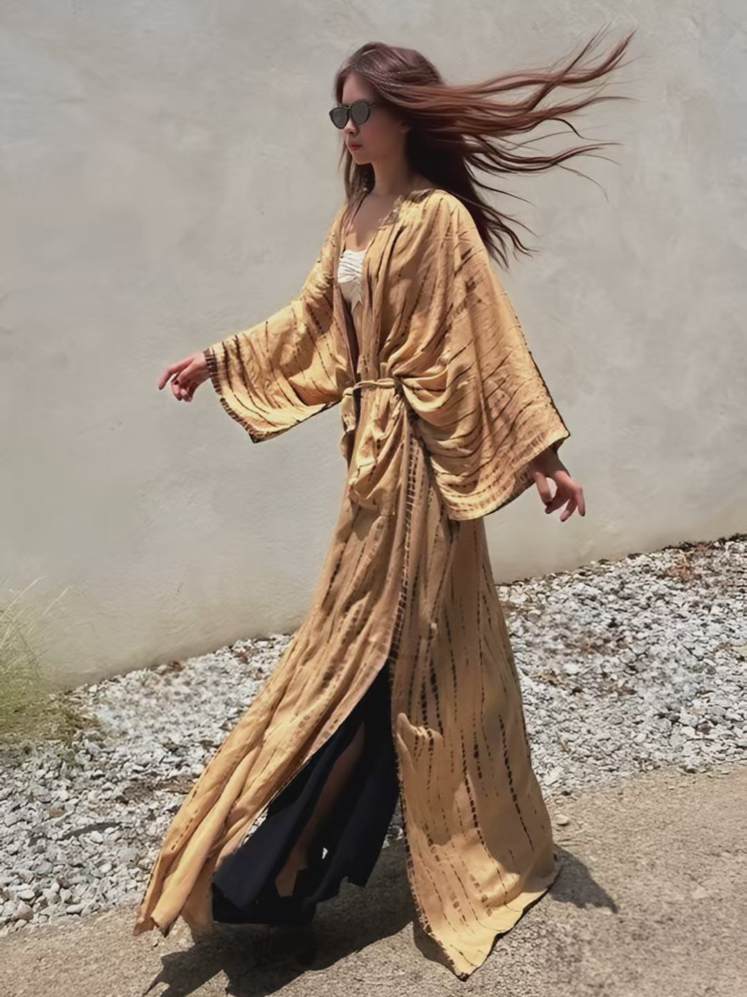 Woman wearing a  tie-dye long kimono robe in tan from Coco de Chom. The oversized robe features long sleeves, a waist tie, and a relaxed, boho-style fit.