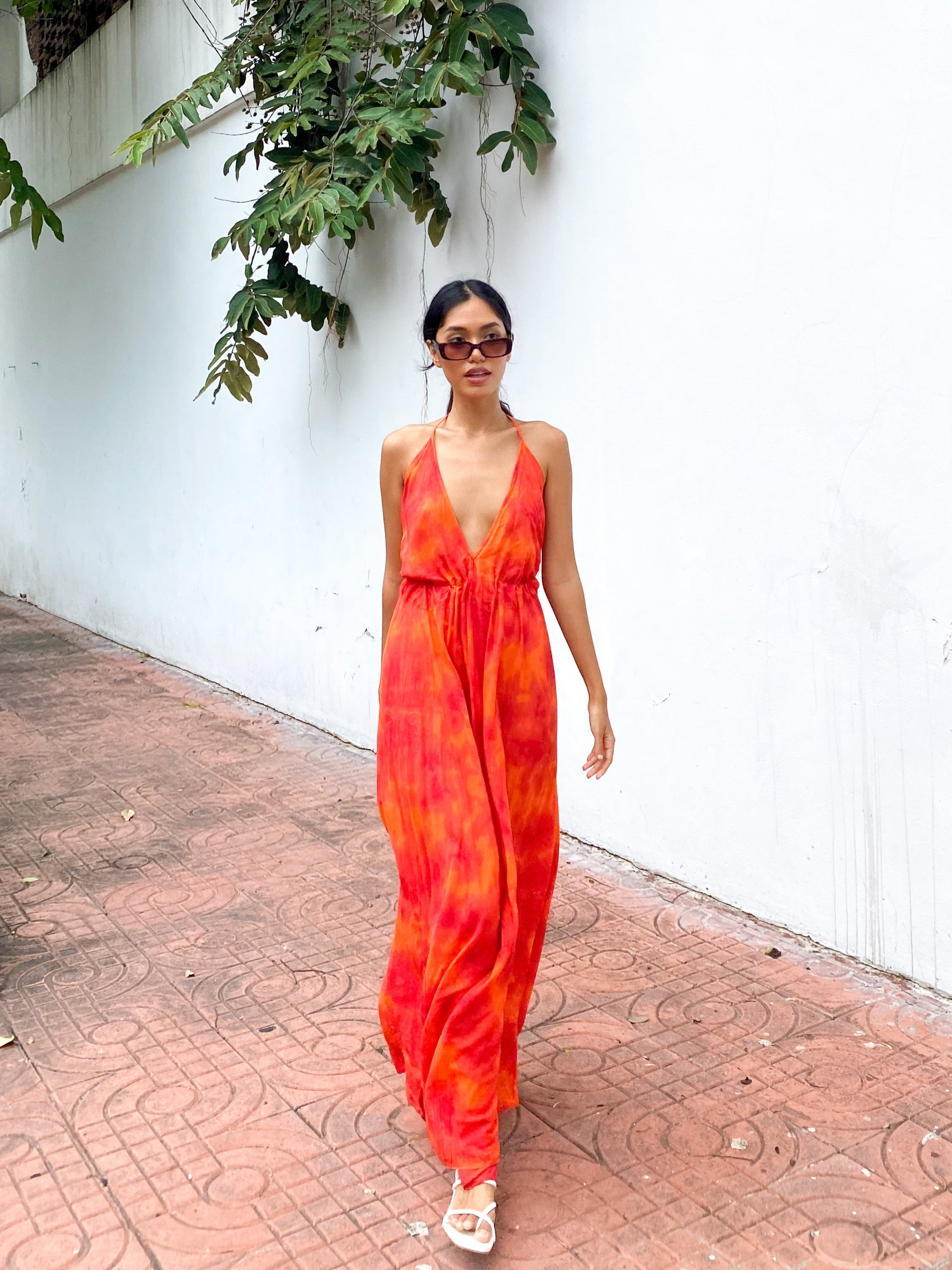 Woman wearing an orange tie-dye open Back Halter Maxi Dress in vibrant orange tie-dye, featuring a flowing maxi length and backless halter design—perfect vacation dress by Coco De Chom.